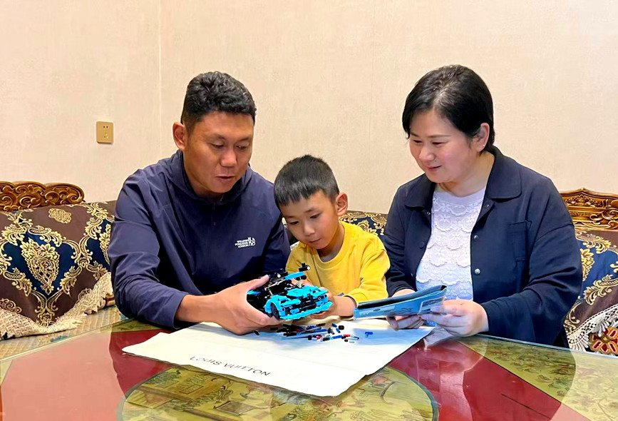 贾珂珂与丈夫罗布次仁陪伴着儿子，一家人围坐在桌前共同拼装模型。受访者供图
